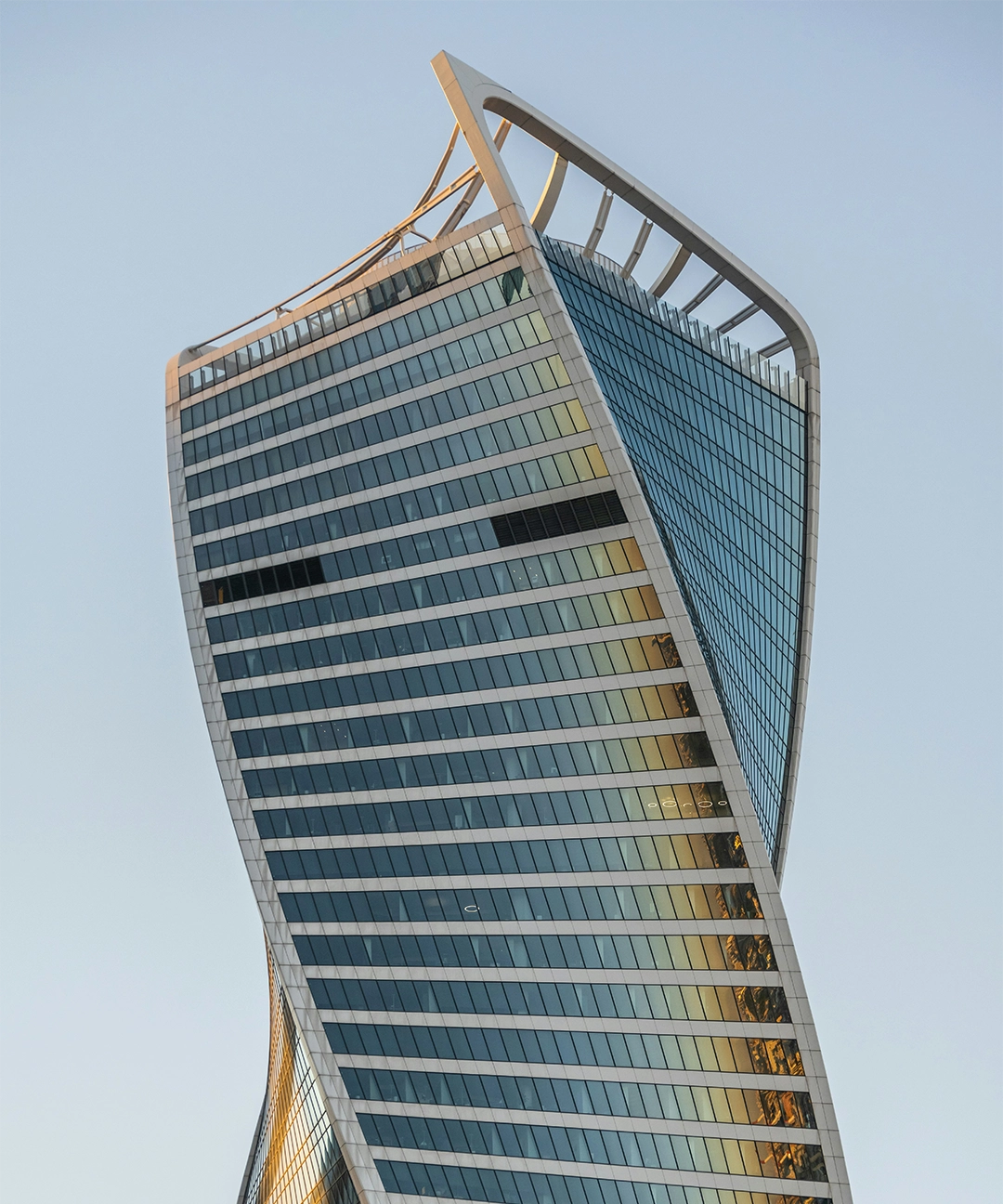 Modern high-rise building with a twisted design and reflective glass windows against a clear sky.