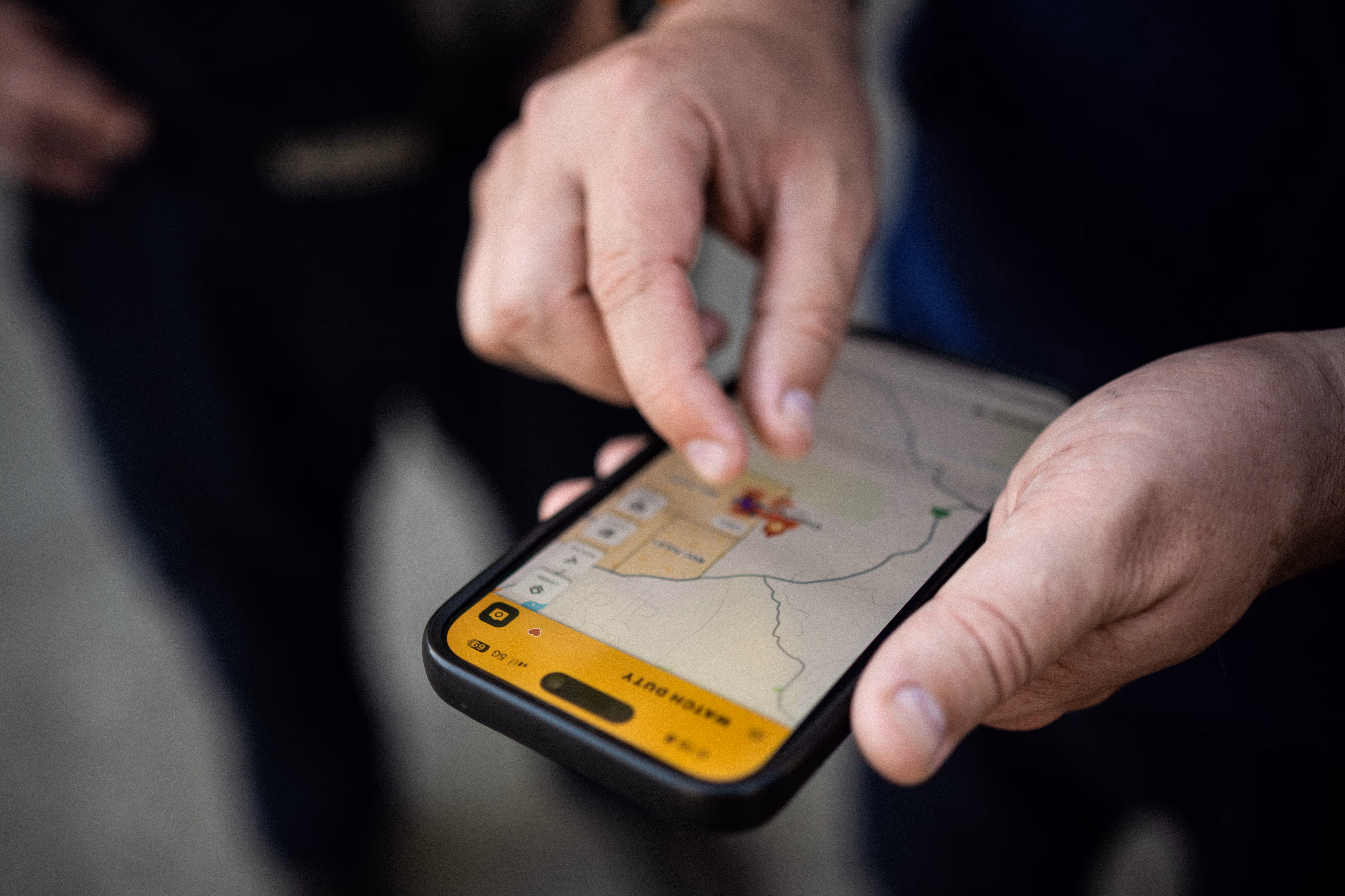A person using a smartphone to view a Watch Duty map with a fire safety section highlighted.