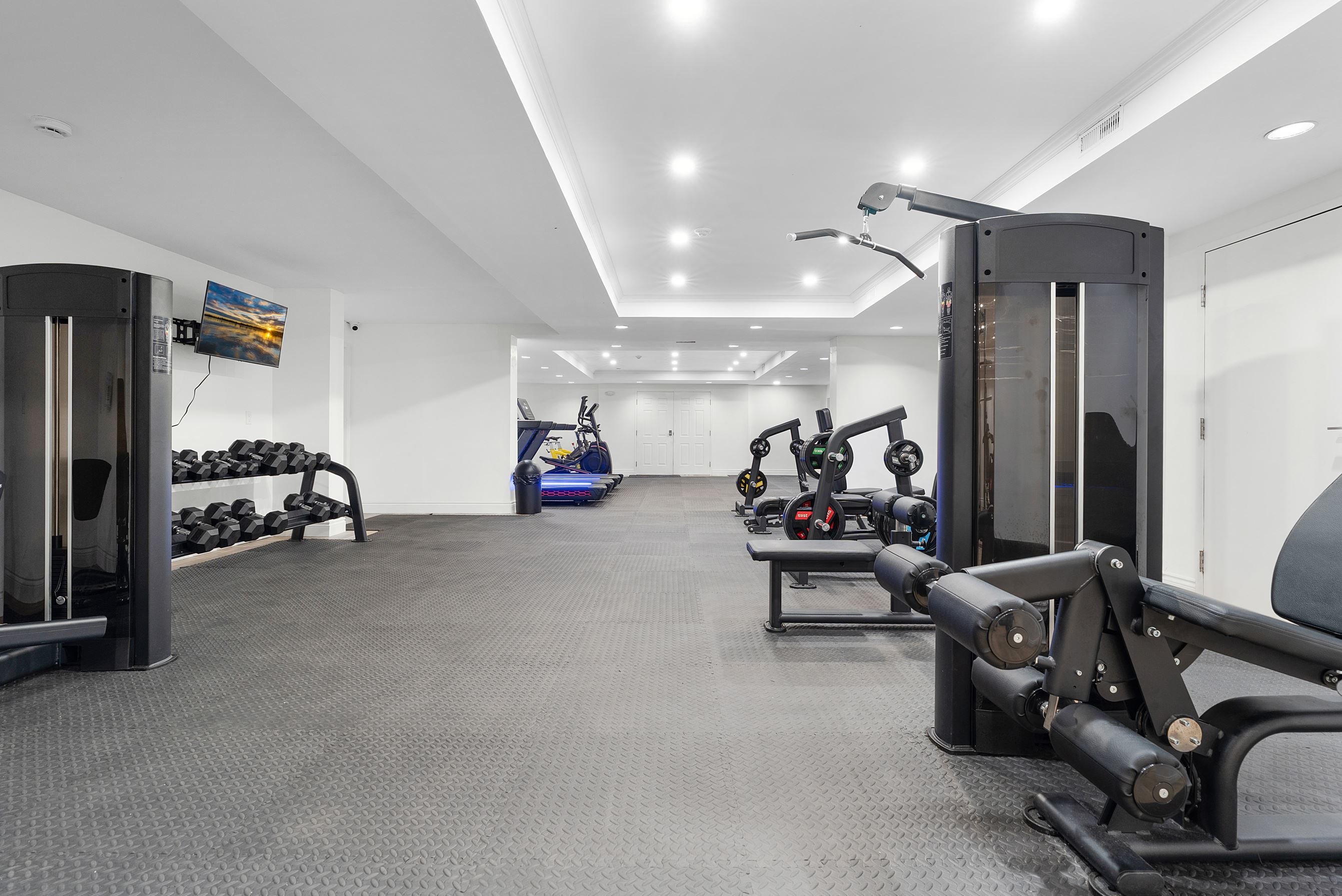 Bright living room with stone fireplace, green sofas, gray armchairs, round coffee table, and wooden floor.