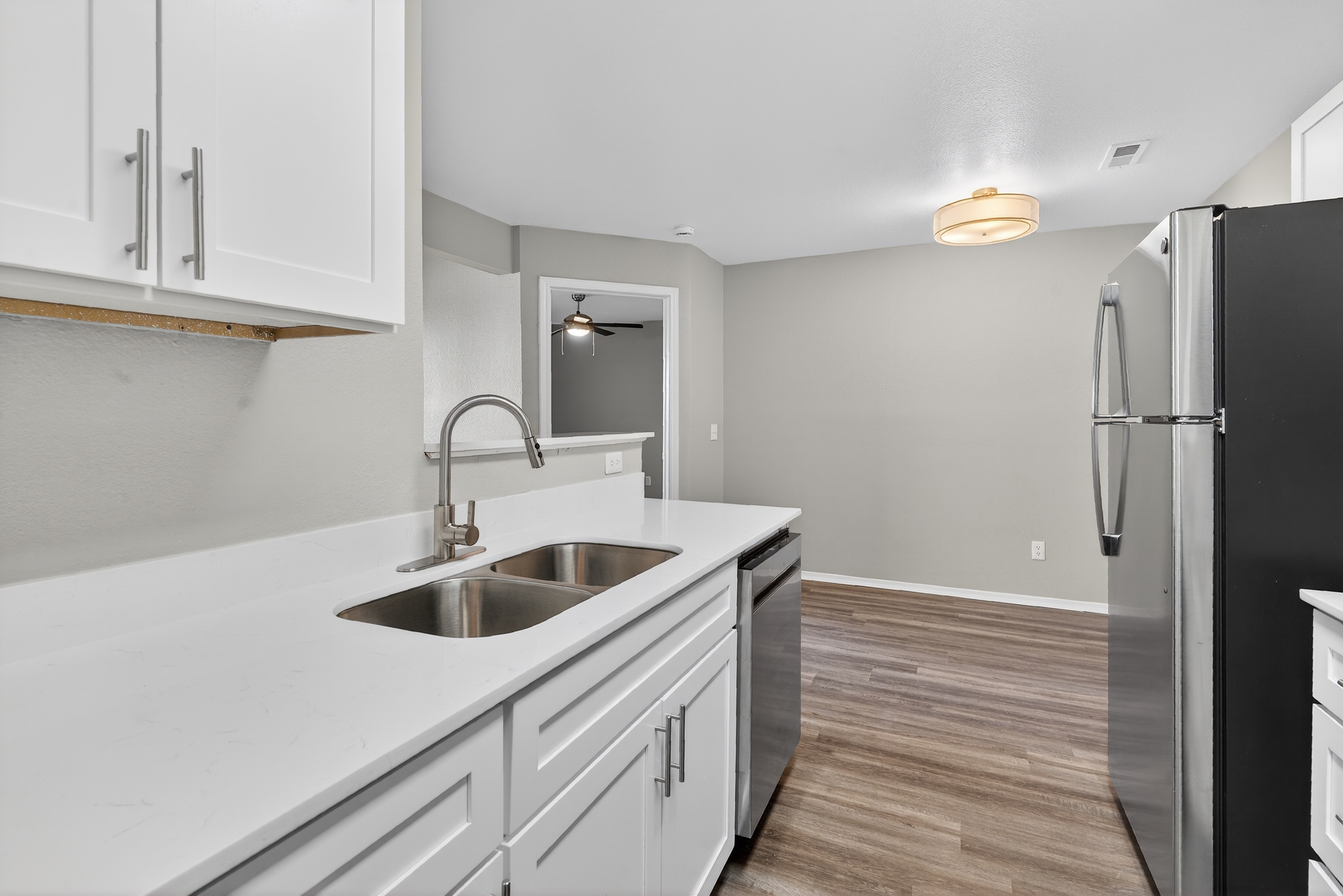 Kitchen with stainless steel appliances and white cabinets and view into dining room