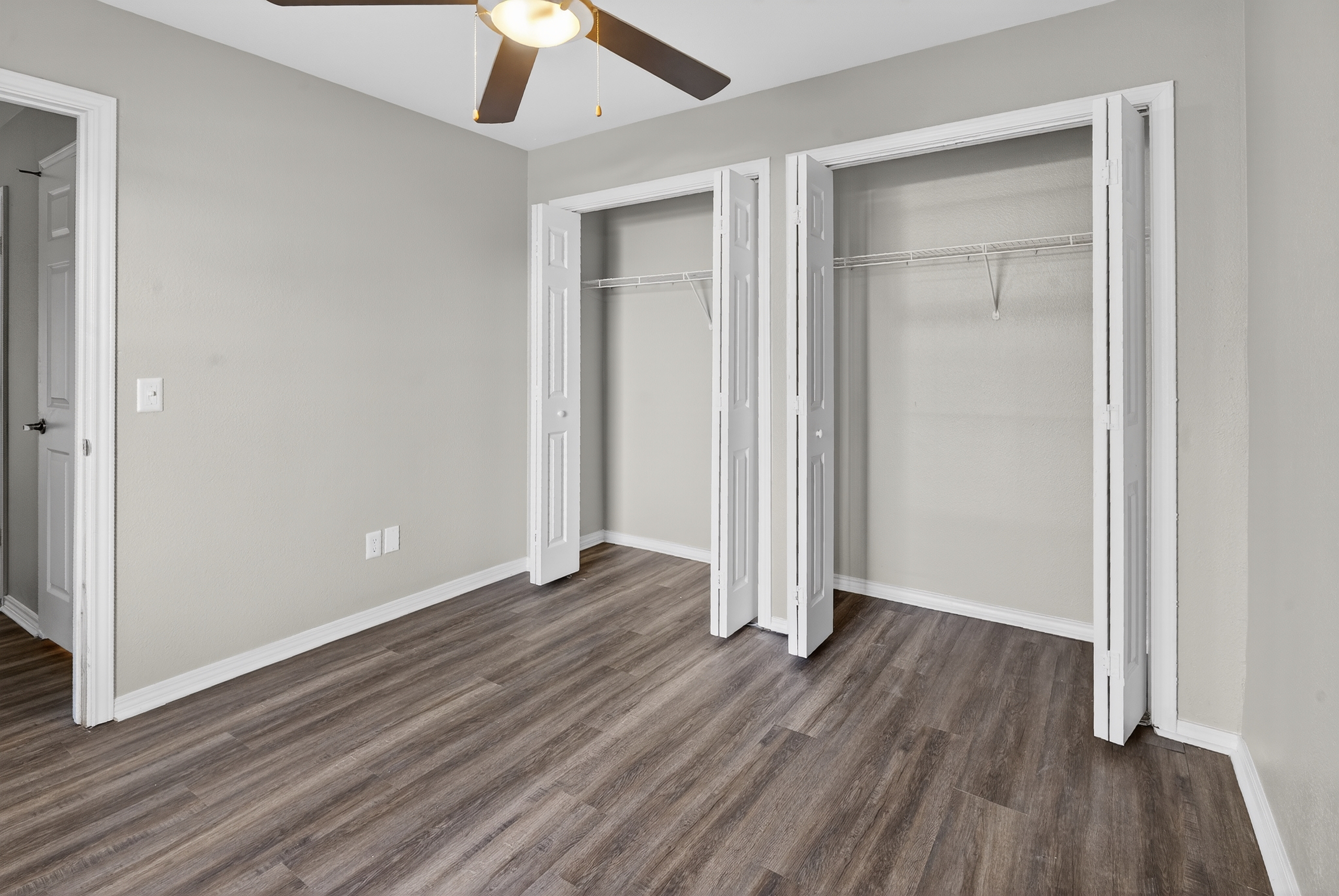 Unfurnished bedroom with ceiling fan and two closets