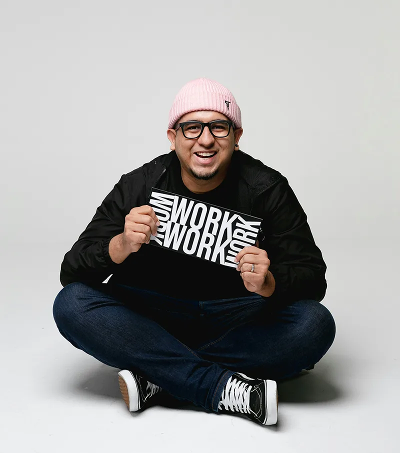 Portrait of a man sitting casually in sweatshirt and cap.
