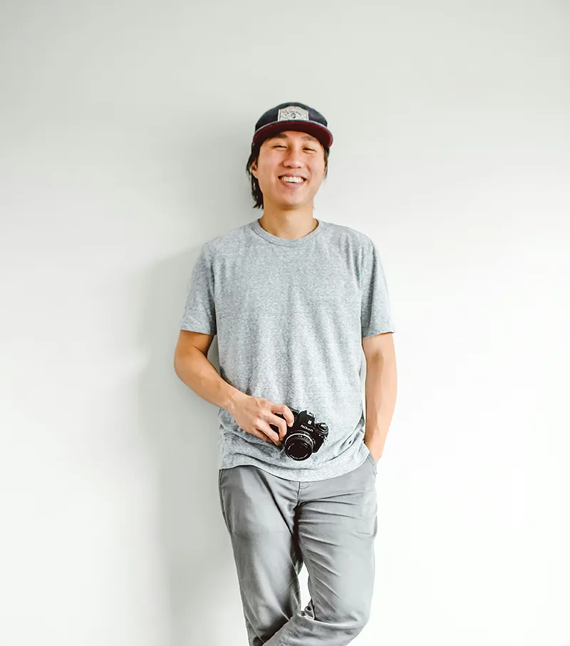 Portrait of a man standing casually in white t-shirt against white background.