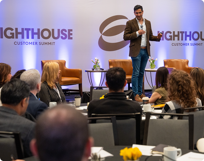 Eudia CEO speaking on stage at Lighthouse Customer Summit with seated audience in foreground.