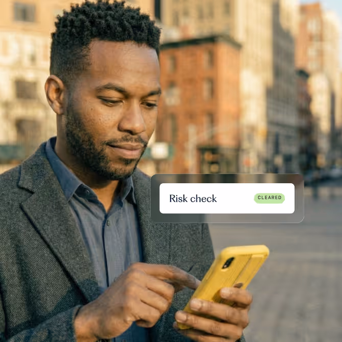 A man using a yellow phone while standing on the street