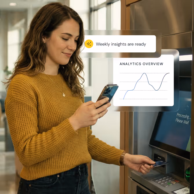 A woman checking her phone while using an ATM