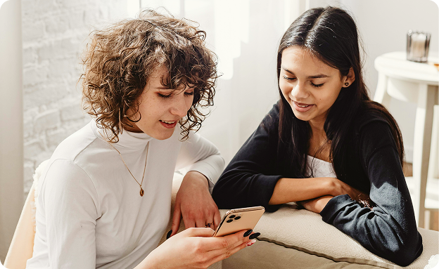 Two women conversing while looking at a phone