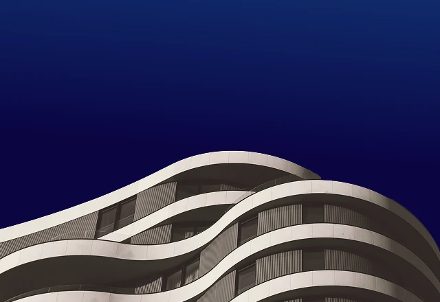 Modern building with smooth, curved balconies against a deep blue sky.