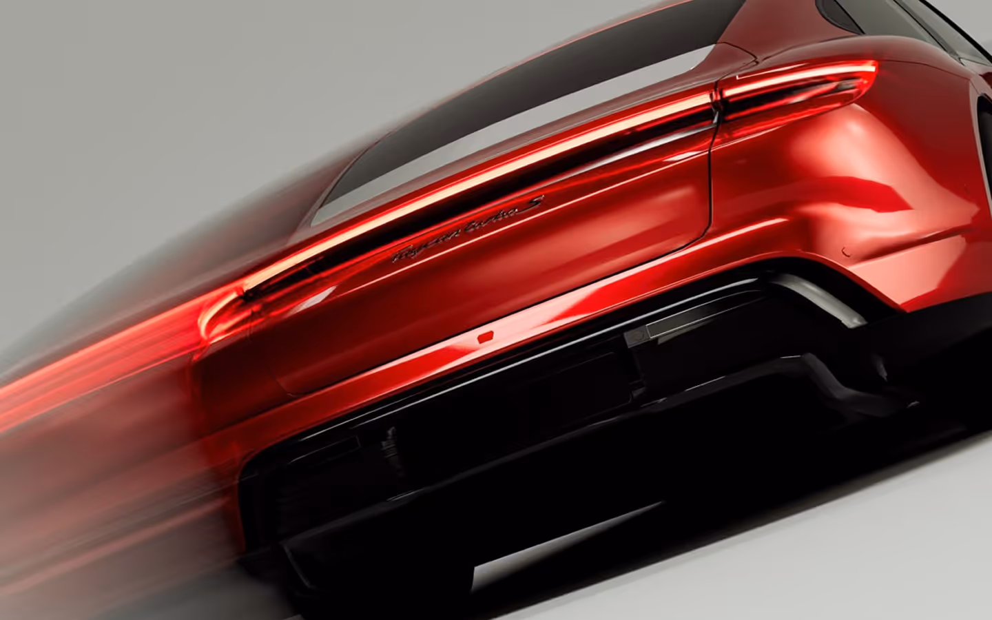 Rear view of a red Porsche Taycan Turbo S with taillights illuminated.