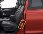 Close-up of the open front driver's side door of a red car with black leather interior seats.