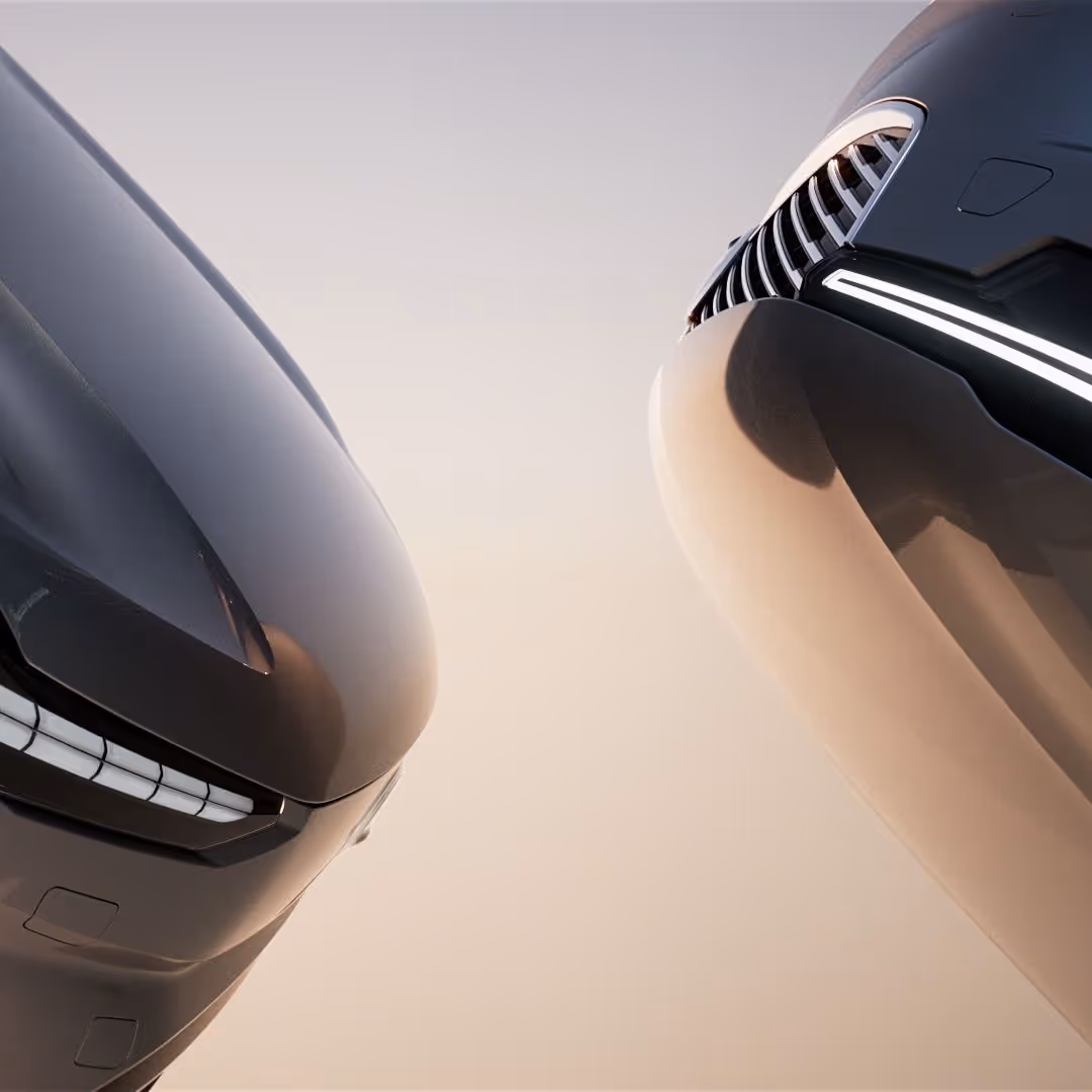 Close-up of the front ends of two sleek, black modern cars facing each other with illuminated headlights against a light background.