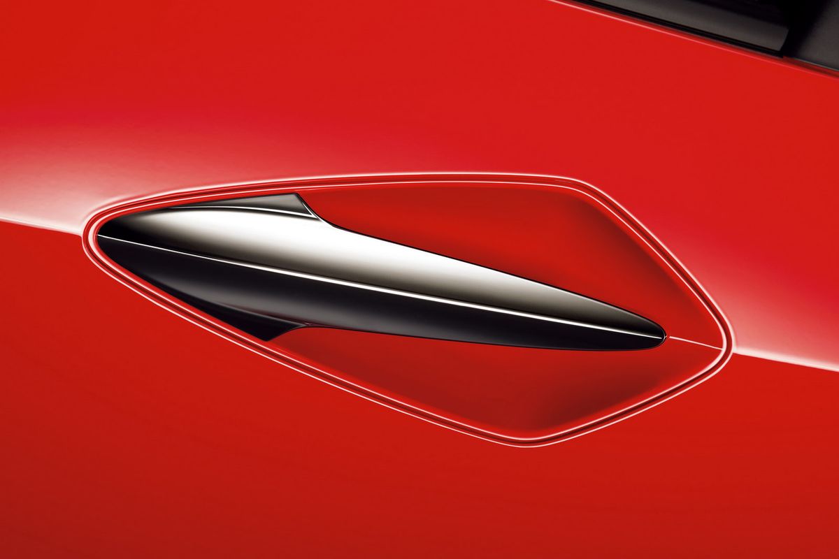 Close-up of a sleek, black side air vent on a red sports car.