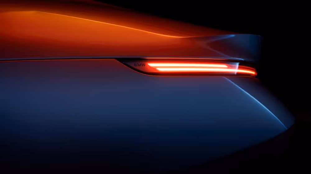 Close-up of a sleek car's rear light illuminated in red against a dark background.