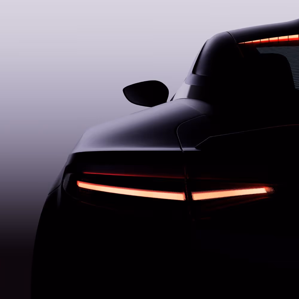 Rear view of a modern car with illuminated horizontal taillights against a gradient background.