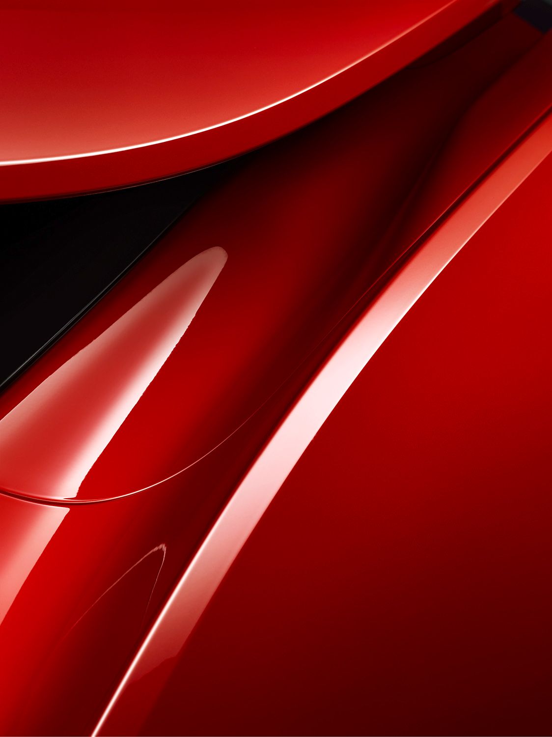 Close-up of glossy red curved surfaces with reflections and shadows.