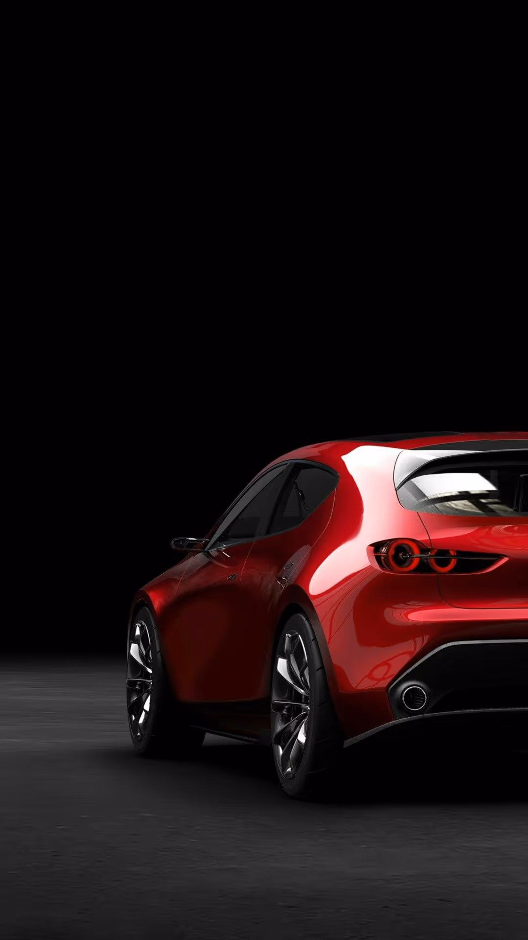 Rear side view of a shiny red sports car with black rims on a dark background.