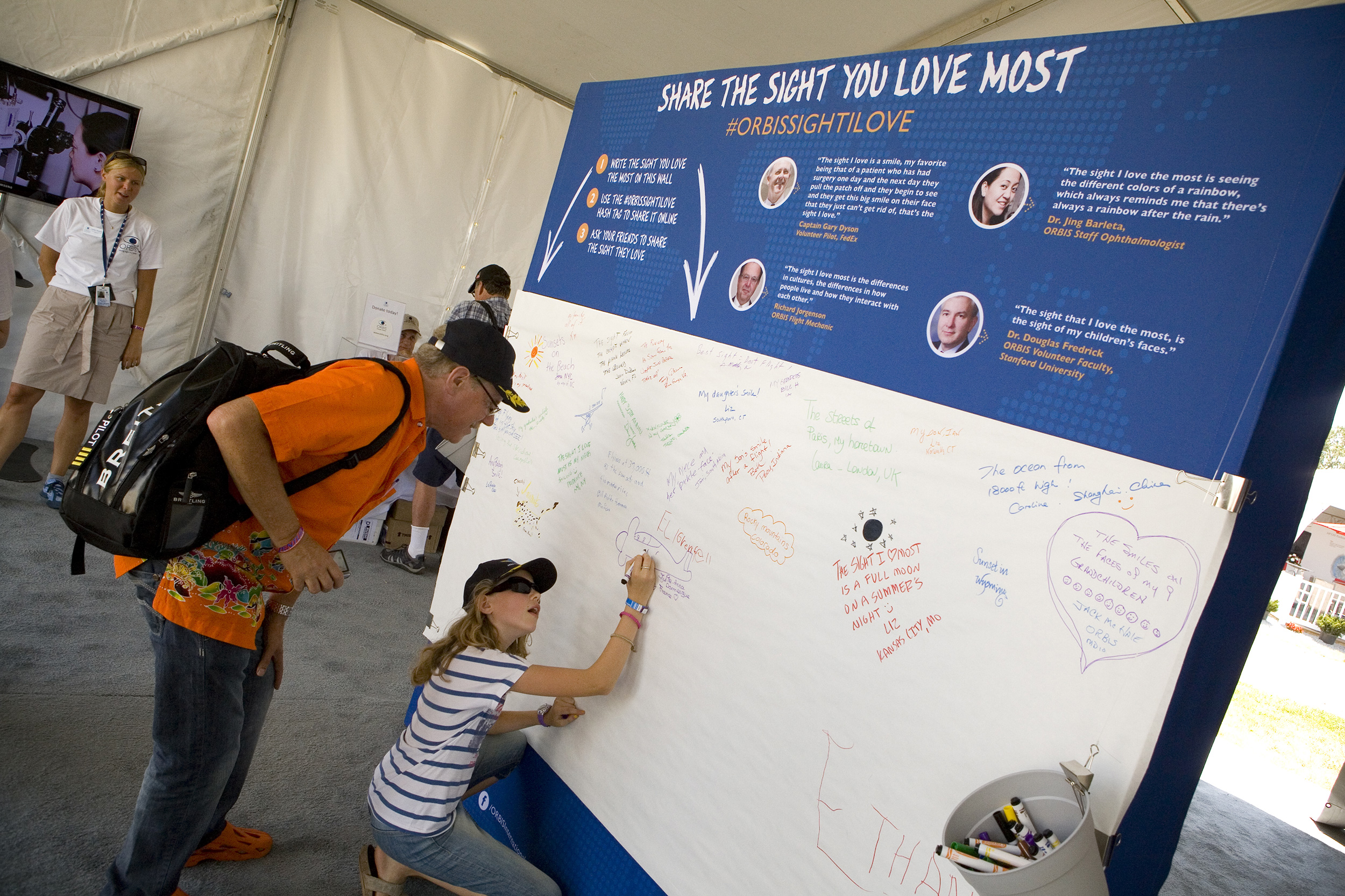 Girl writes on Orbis exhibit banner