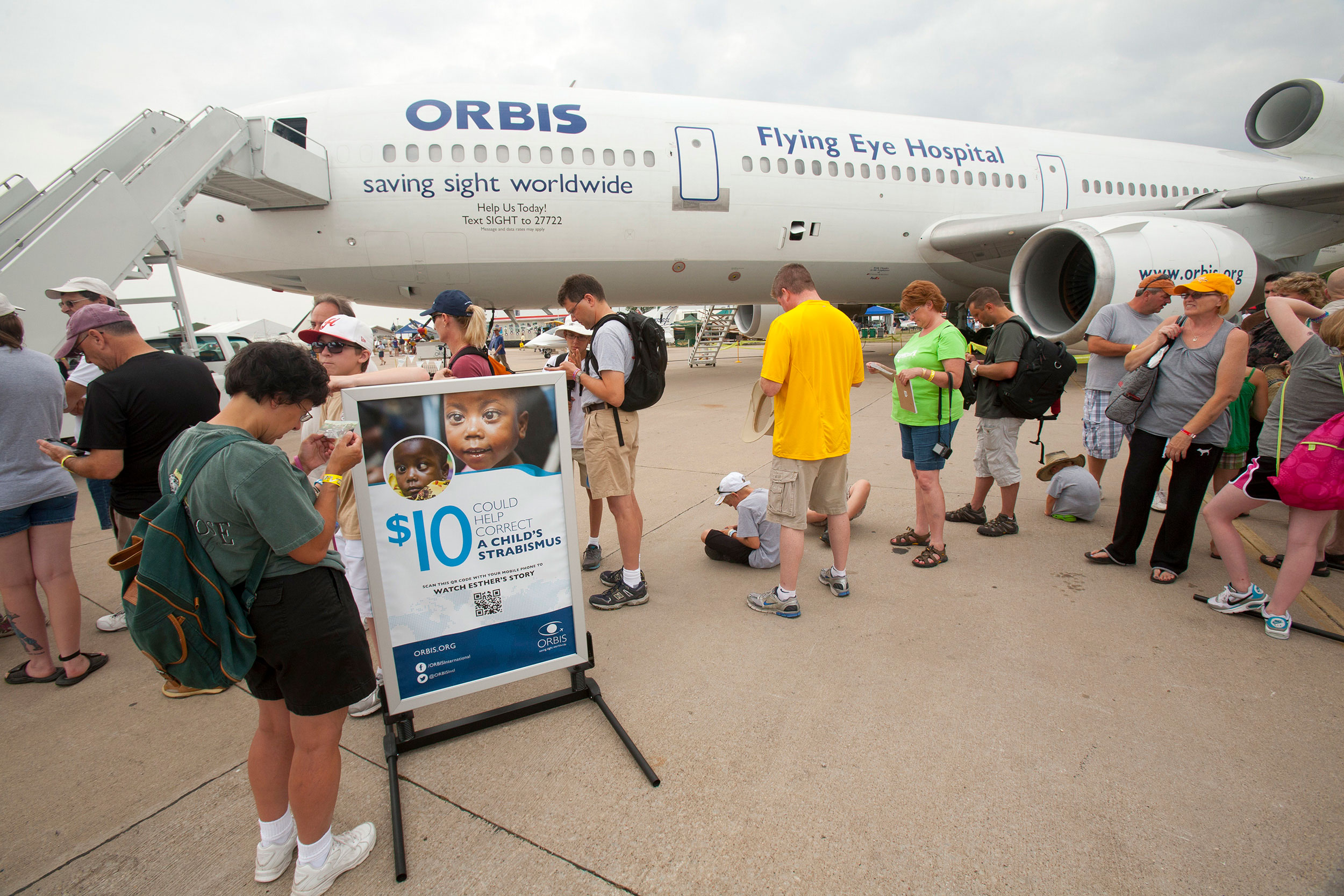 woman standing beside Orbis exhibit stand