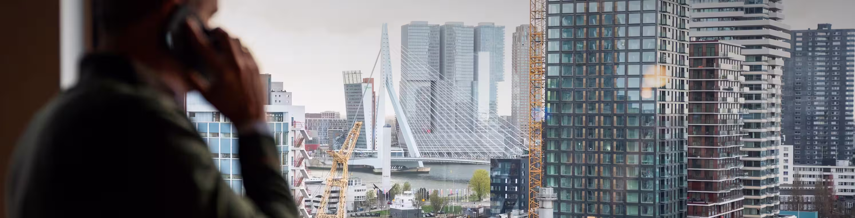 Three men sitting at a conference table with laptops, one drinking from a cup.