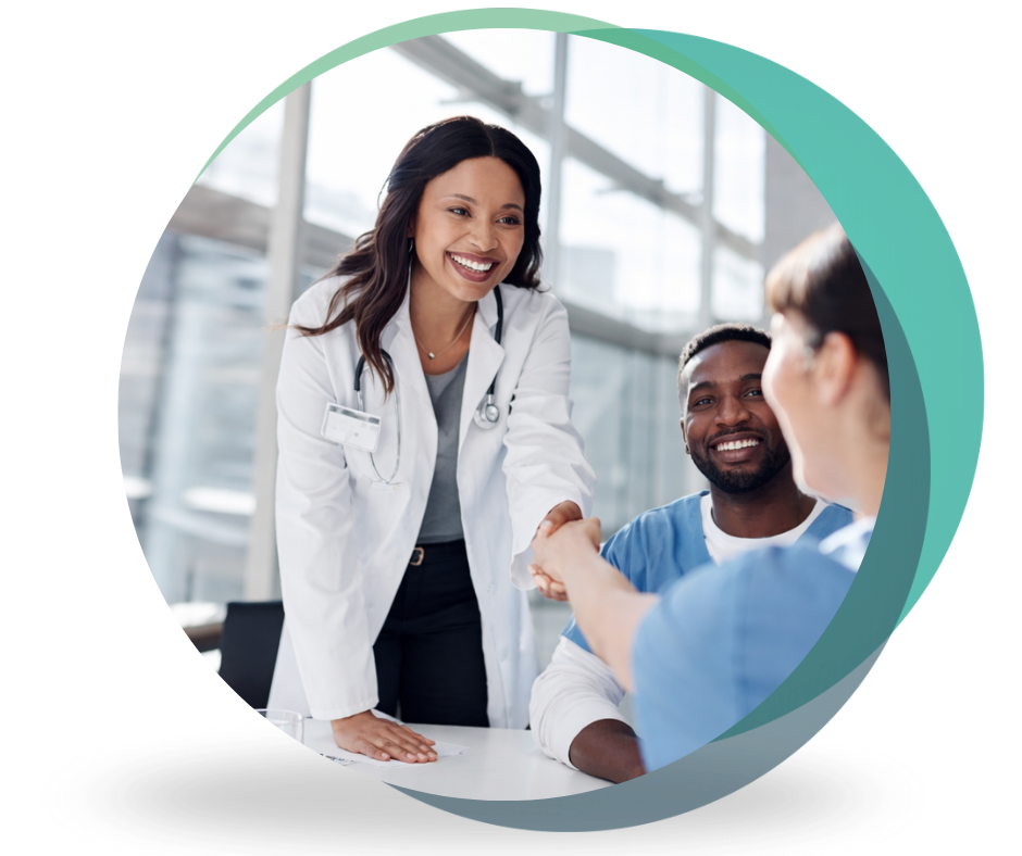 A smiling doctor in a white lab coat shaking hands with a healthcare professional across a table, with a second team member looking on in a bright clinical office setting.