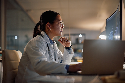 Healthcare professional reviewing medical imaging data on a computer during clinical research analysis.