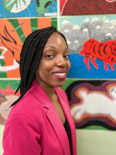 Mary Banson smiling in front of colorful student artwork