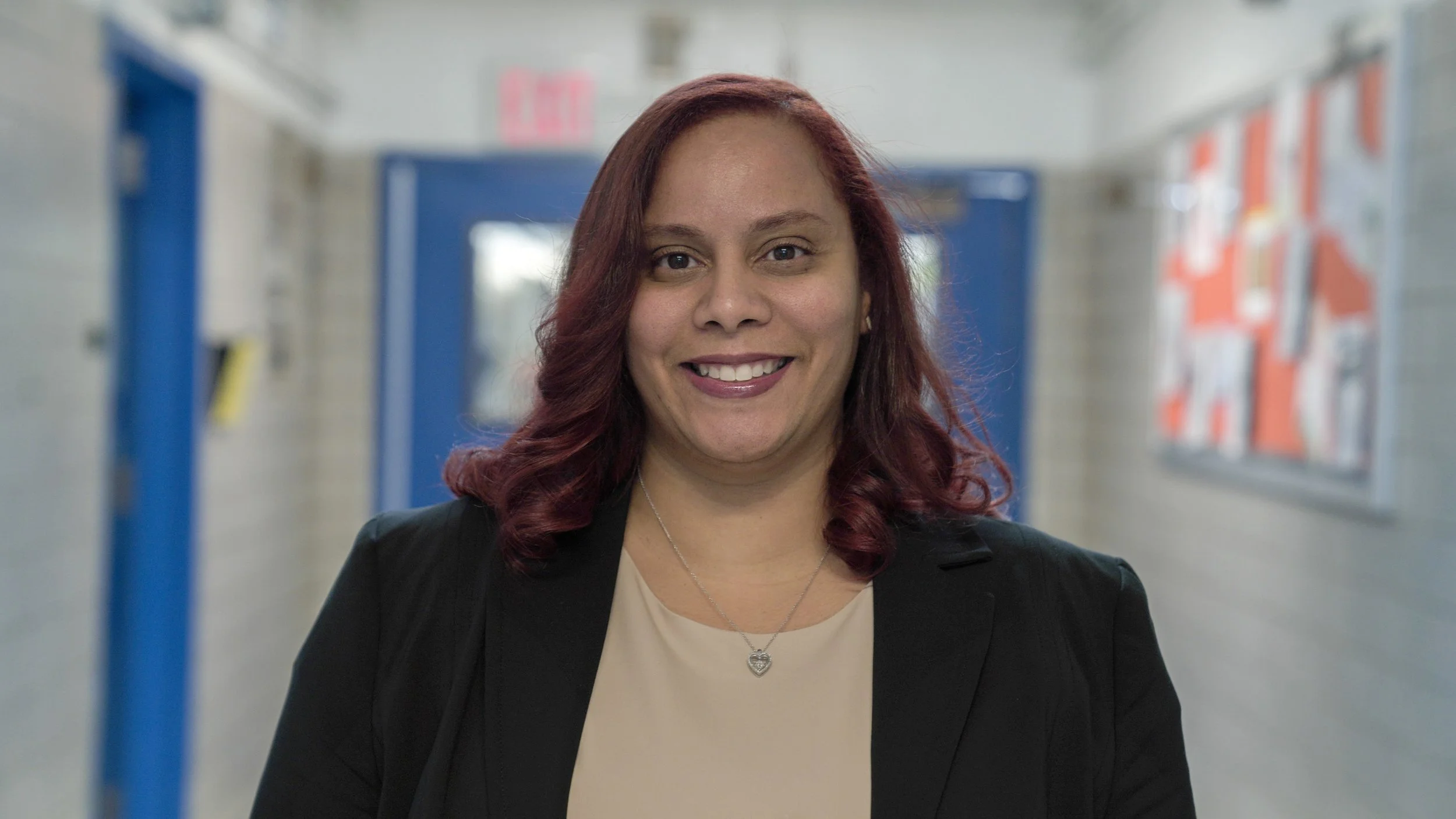 Mayra De Peña smiling in a school hallway