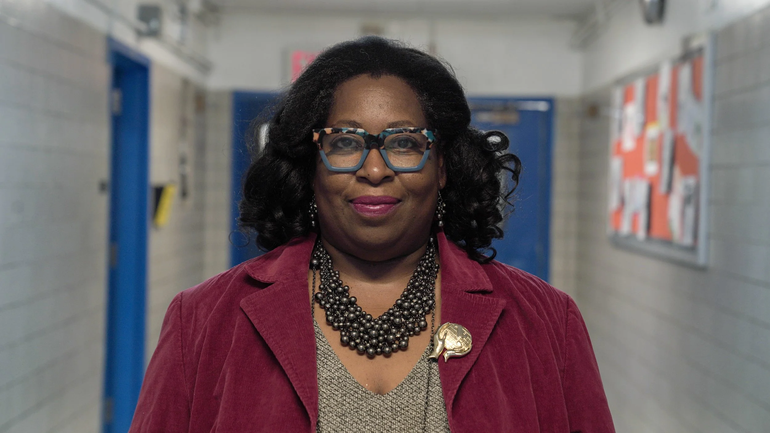 Lorrie Ayers-Hutchinson smiling in a school hallway
