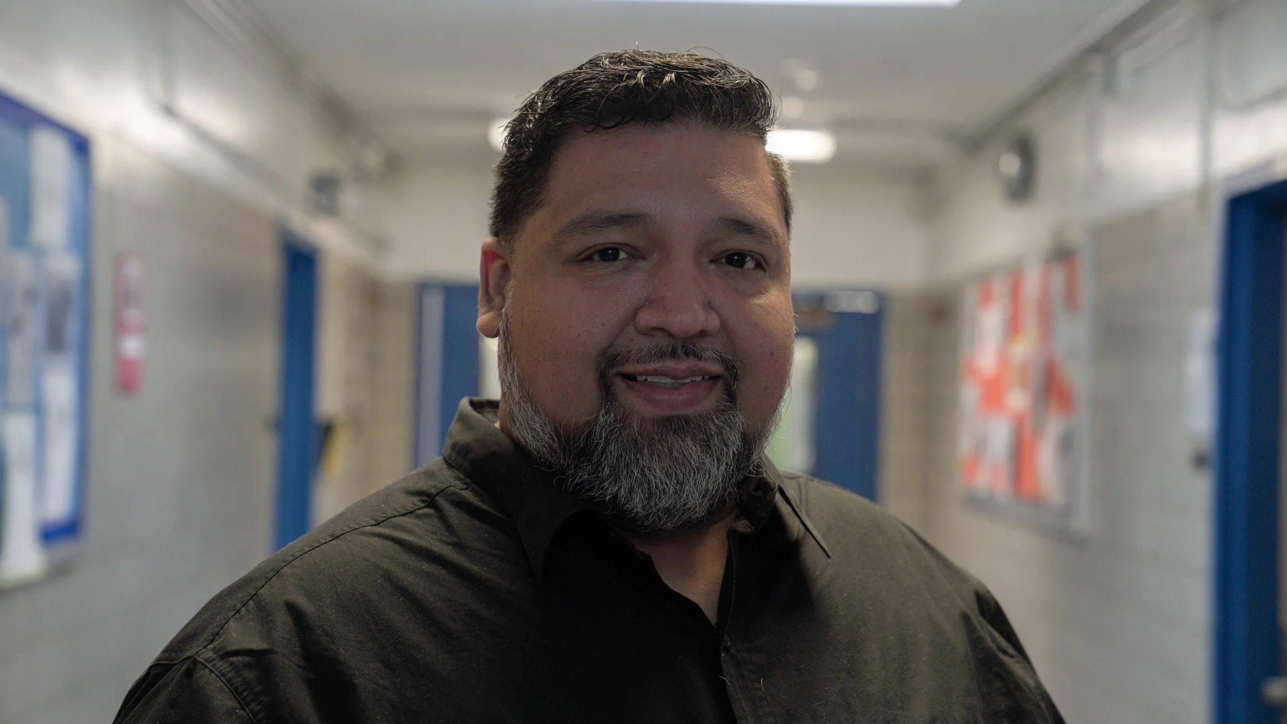 Leonardo Macias smiling in a school hallway