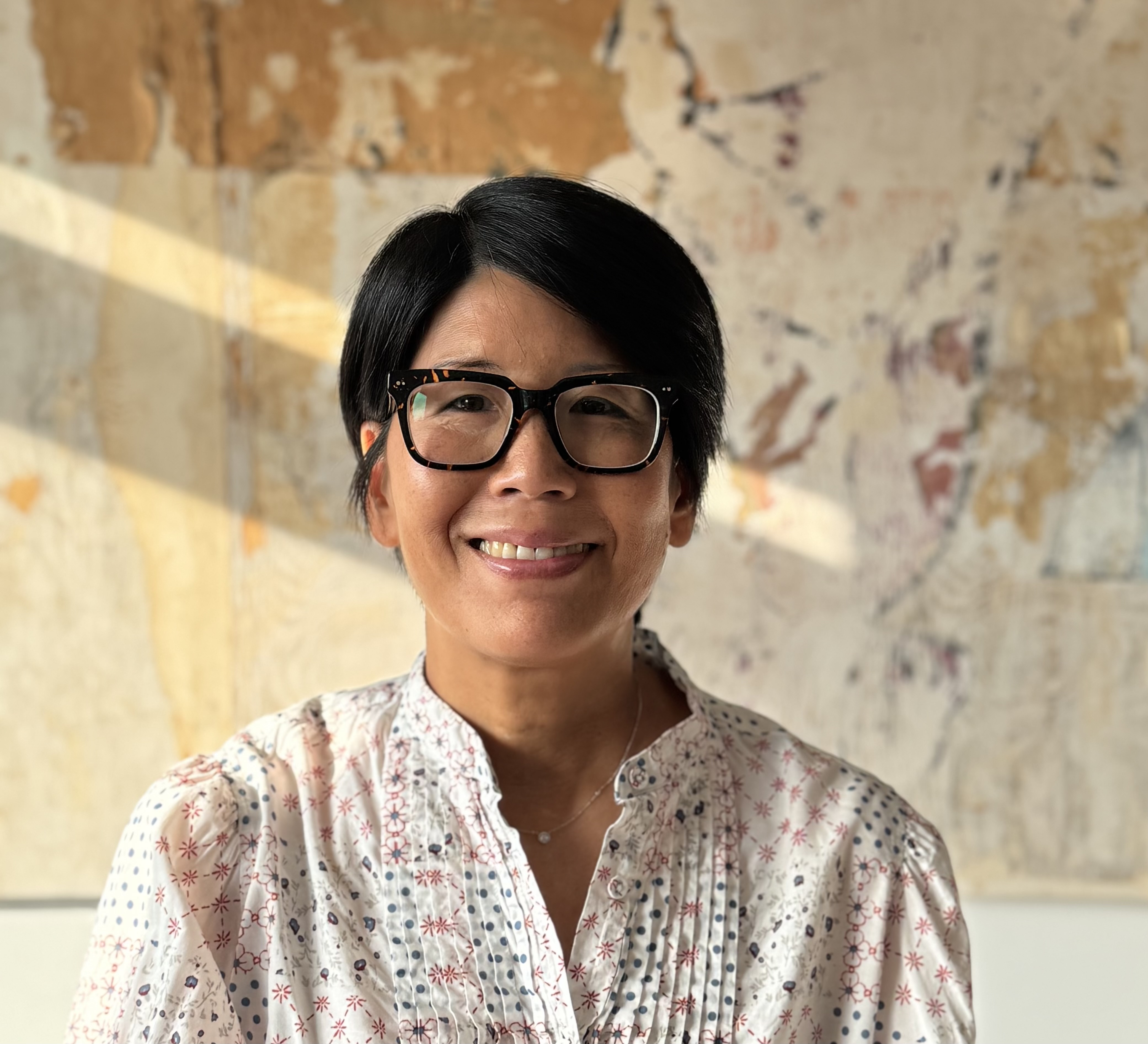 Joyce Shu smiling in front of an abstract artwork