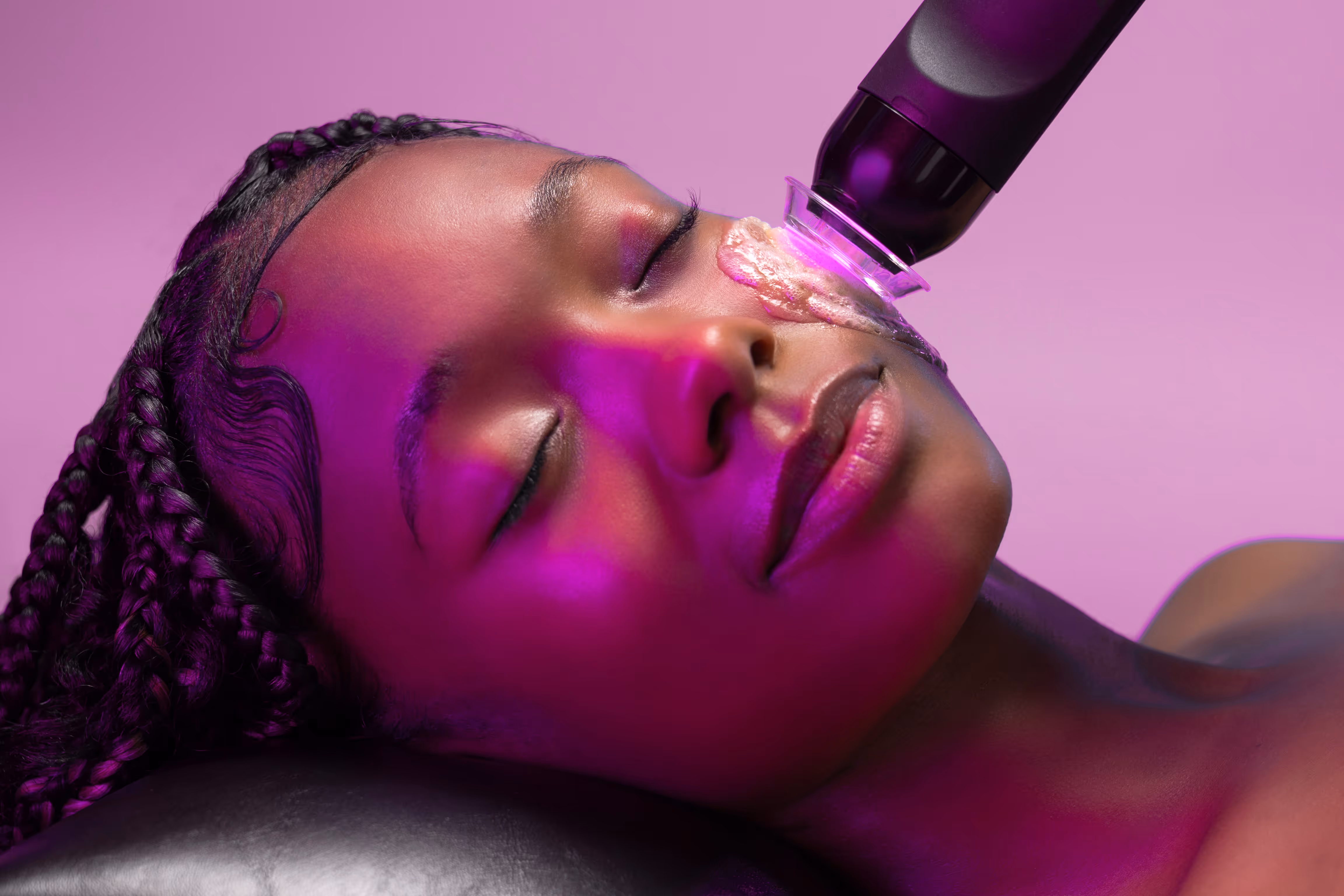 Woman receiving facial treatment with a blue light therapy device at a spa.