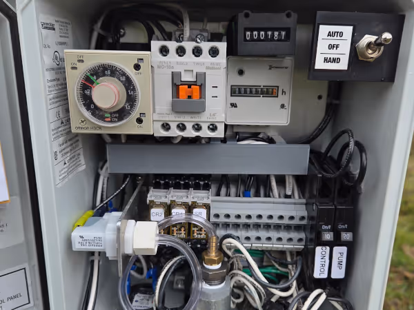 Open electrical control panel showing timer dial, circuit breakers, switches, and wiring connections.