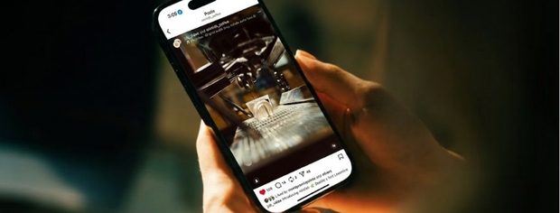 Person holding a smartphone displaying an Instagram post of a coffee cup on a table in a cozy setting.