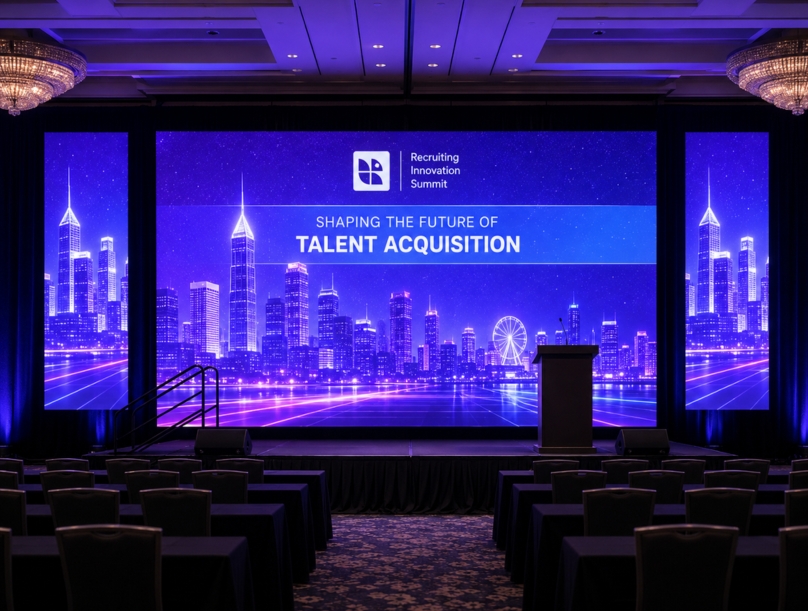 Audio and video control setup for a conference with monitors showing a Recruiting Innovation Summit.