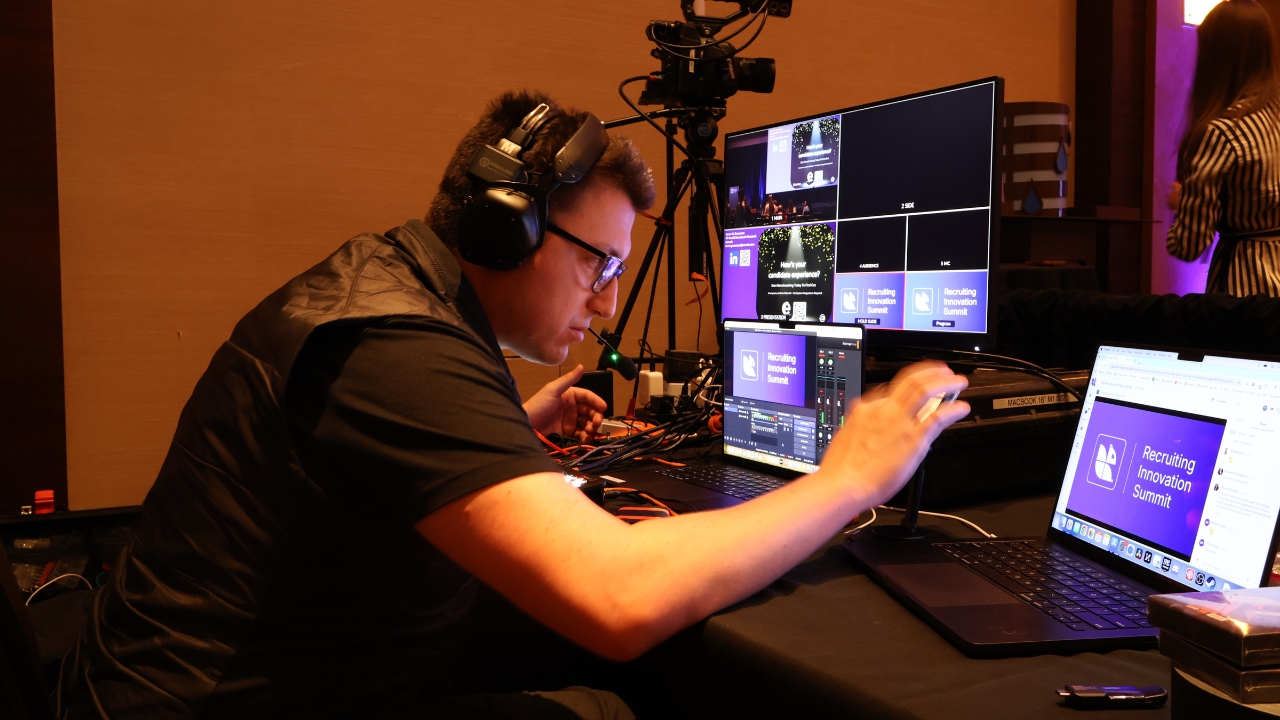 Man operating video production equipment with multiple monitors in professional studio setup
