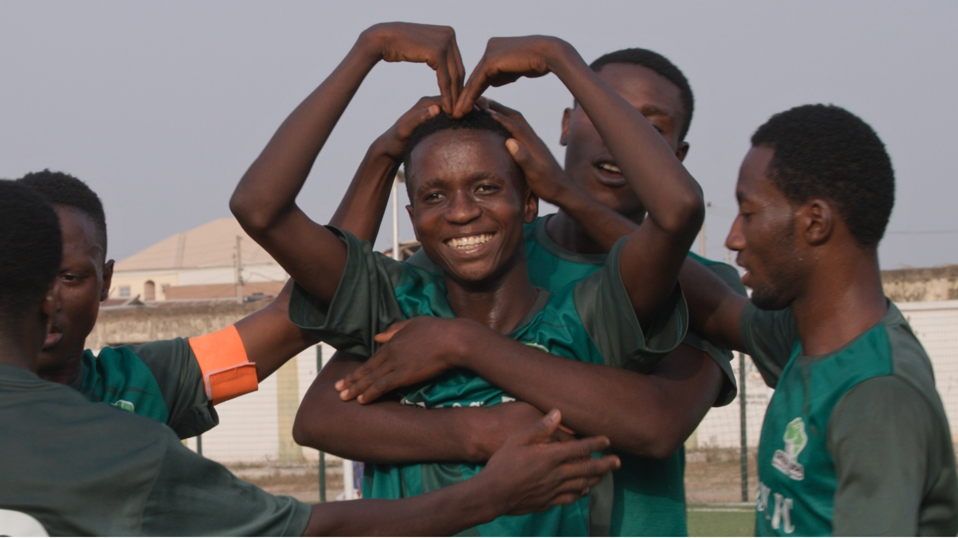 Young athletes in green jerseys making heart gesture together, showing unity and team spirit.