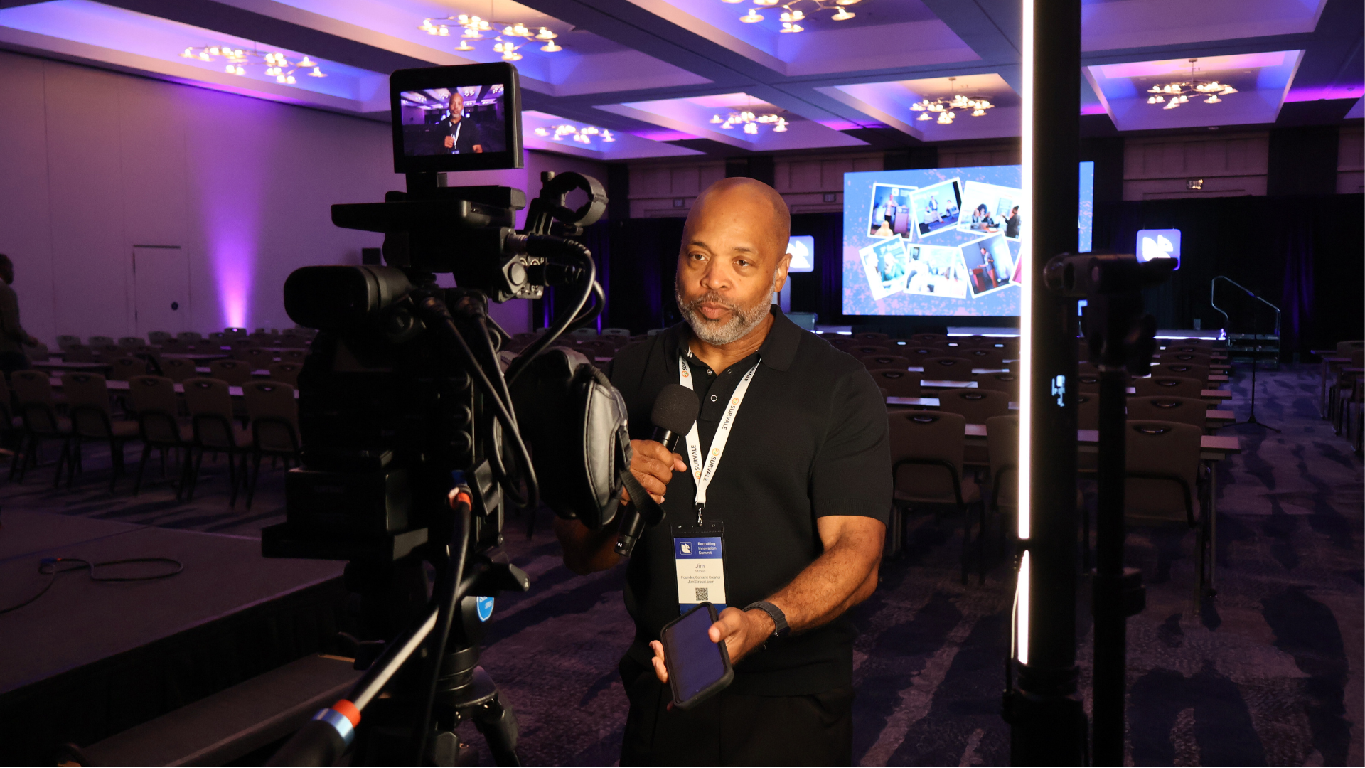Professional cameraman operates broadcast camera in modern conference hall with purple lighting