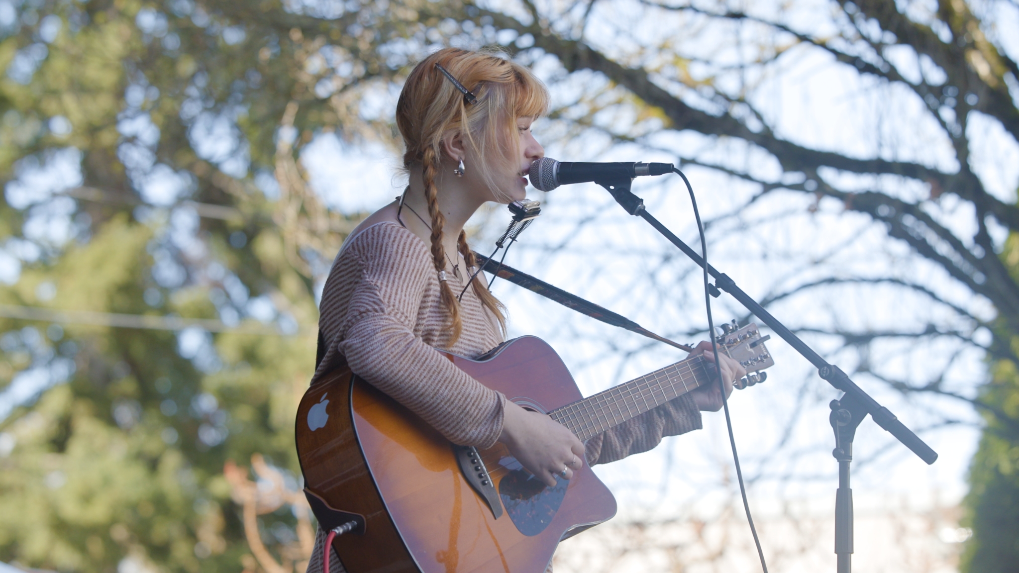 Teen singer-songwriter performing with acoustic guitar outside the Old Fire House Teen Center in Redmond.