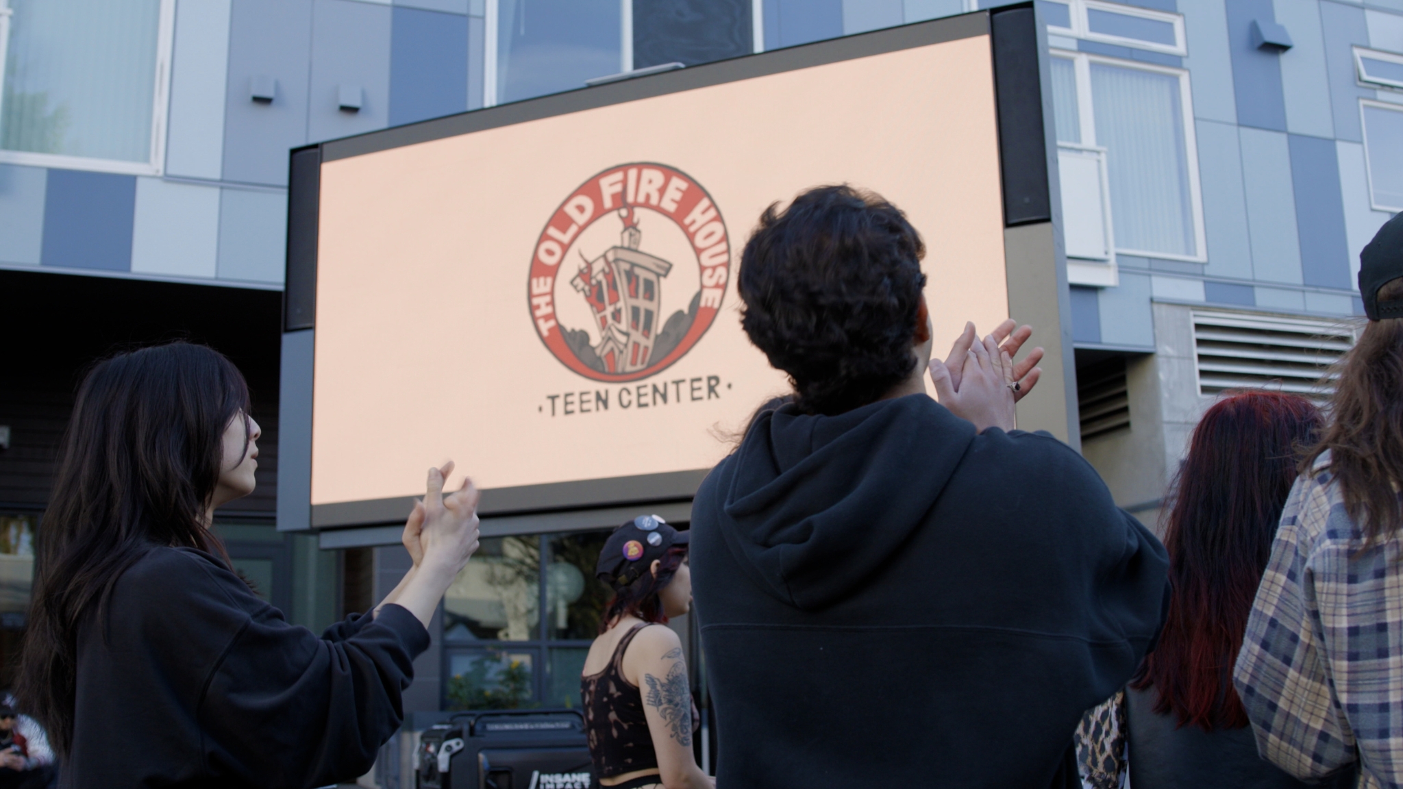 Teens gathered outside the Old Fire House Teen Center in Redmond applaud during a legacy documentary event.