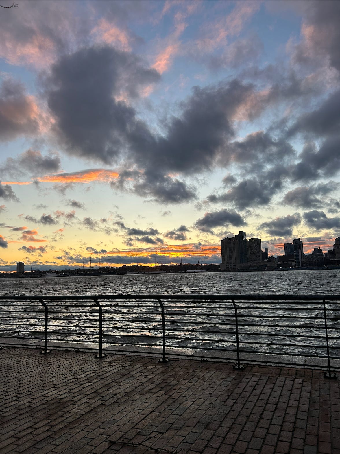 the sky full of choppy clouds and vibrant oranges and yellows over choppy wind-blown waters