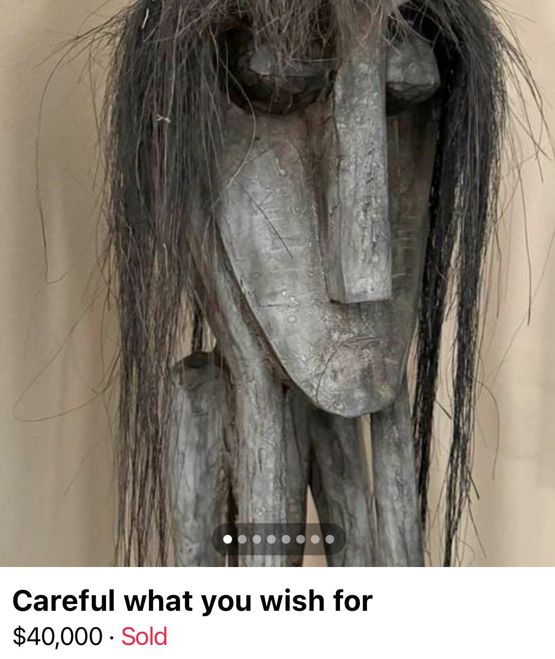a cursed gray wooden sculpture with a large head, 4 spindly legs, and long black hair which appears to be human. the listing title reads, "careful what you wish for," and the item sold for $40,000.