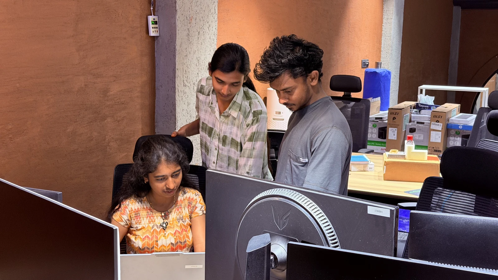 Origin teammates coordinating work at a shared workstation