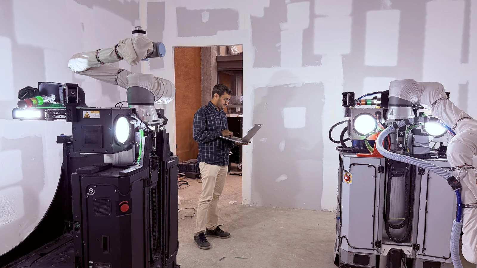 An engineer operating two Origin robots at a test site