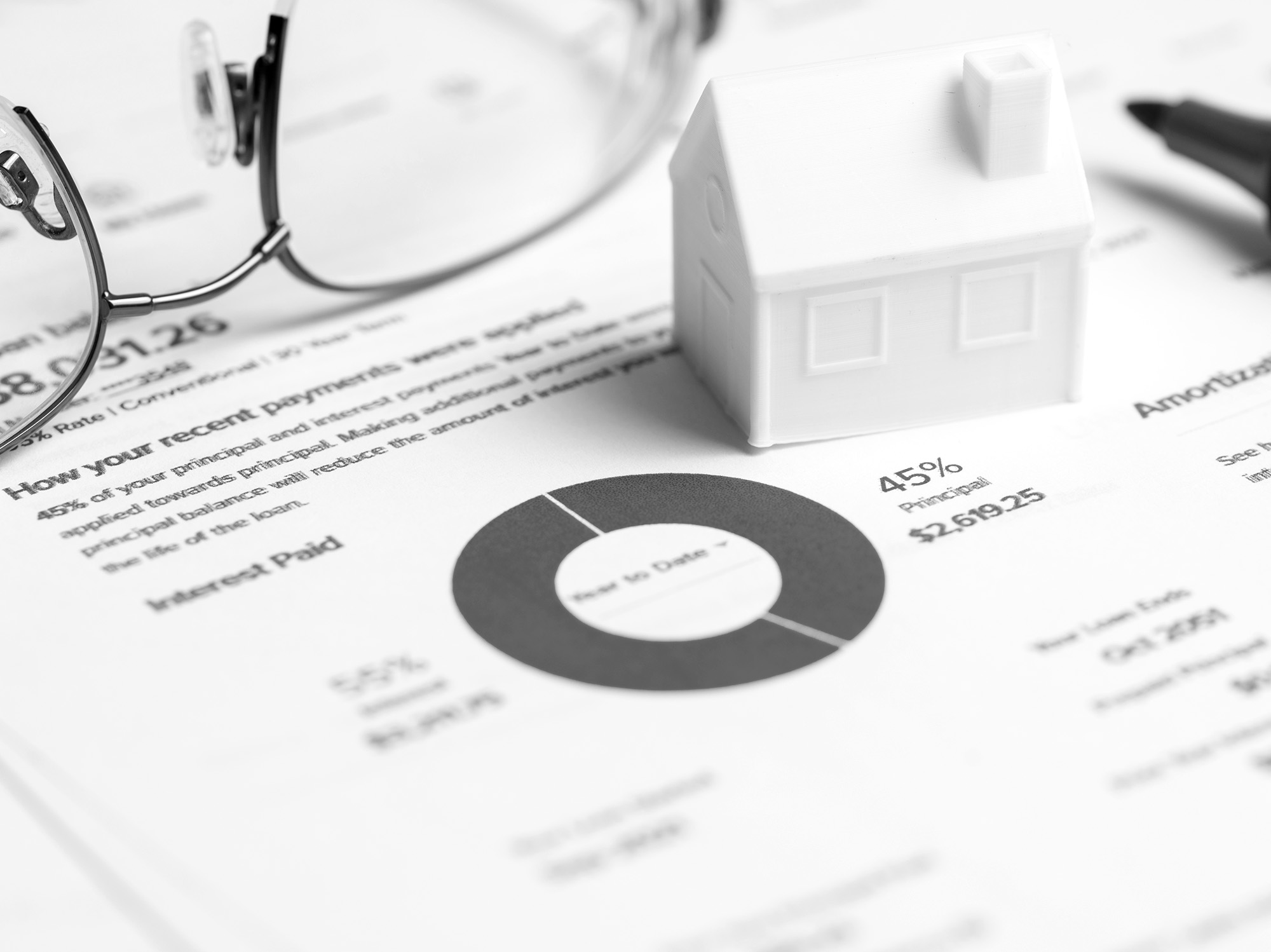 Mortgage loan documents with white house model representing home financing