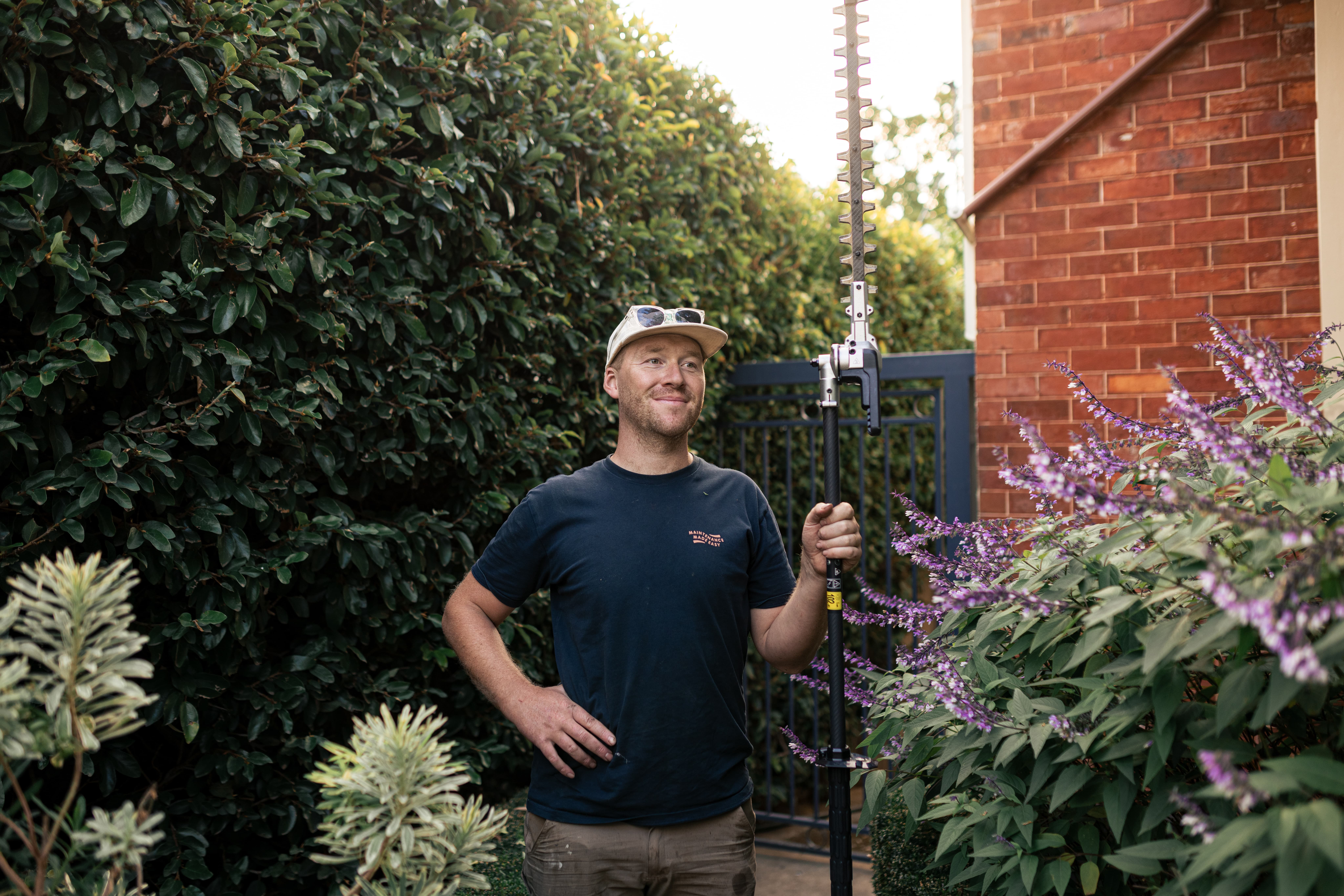 Oscar from Home n Hosed standing beside hedges during residential garden maintenance