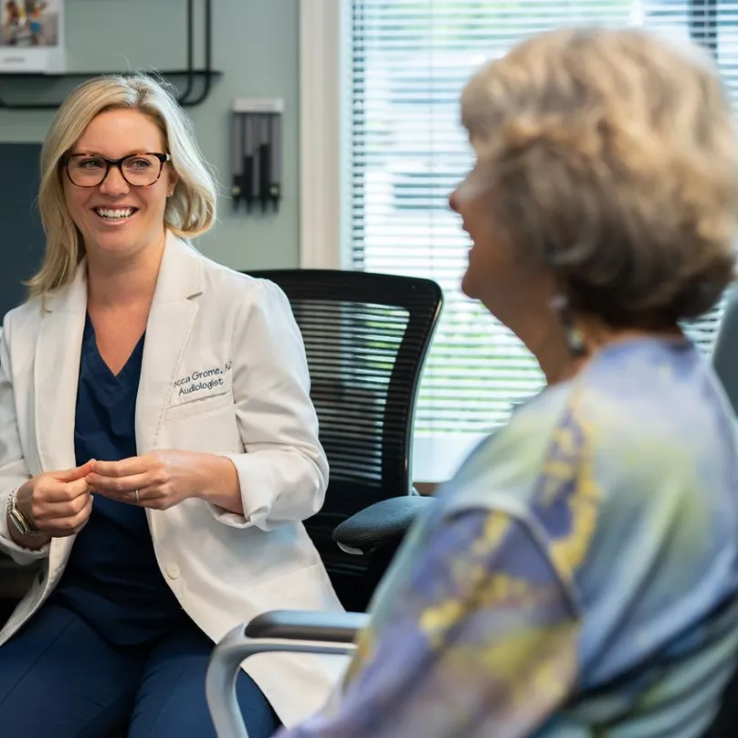 Dr Grome smiling and talking with an elderly female patient in a medical office.