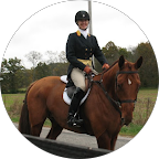 Smiling equestrian rider in a black helmet and jacket sitting on a brown horse outdoors.
