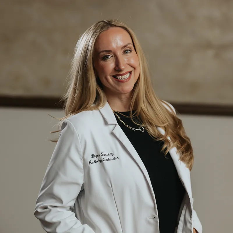 Smiling woman with curly hair, glasses, and a colorful flower crown filter.
