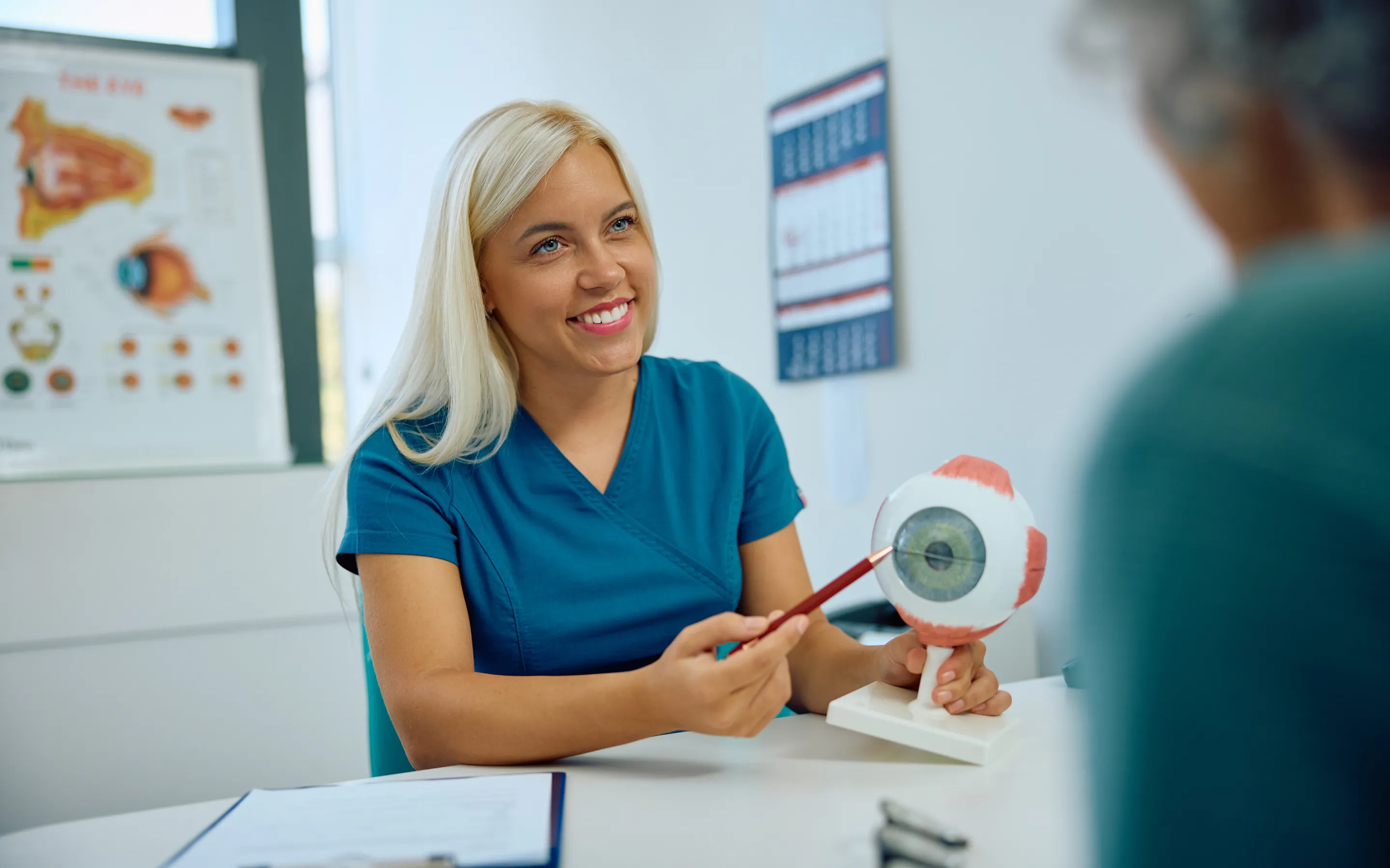 Optometrist explaining eye health and vision using anatomical eye model during patient consultation