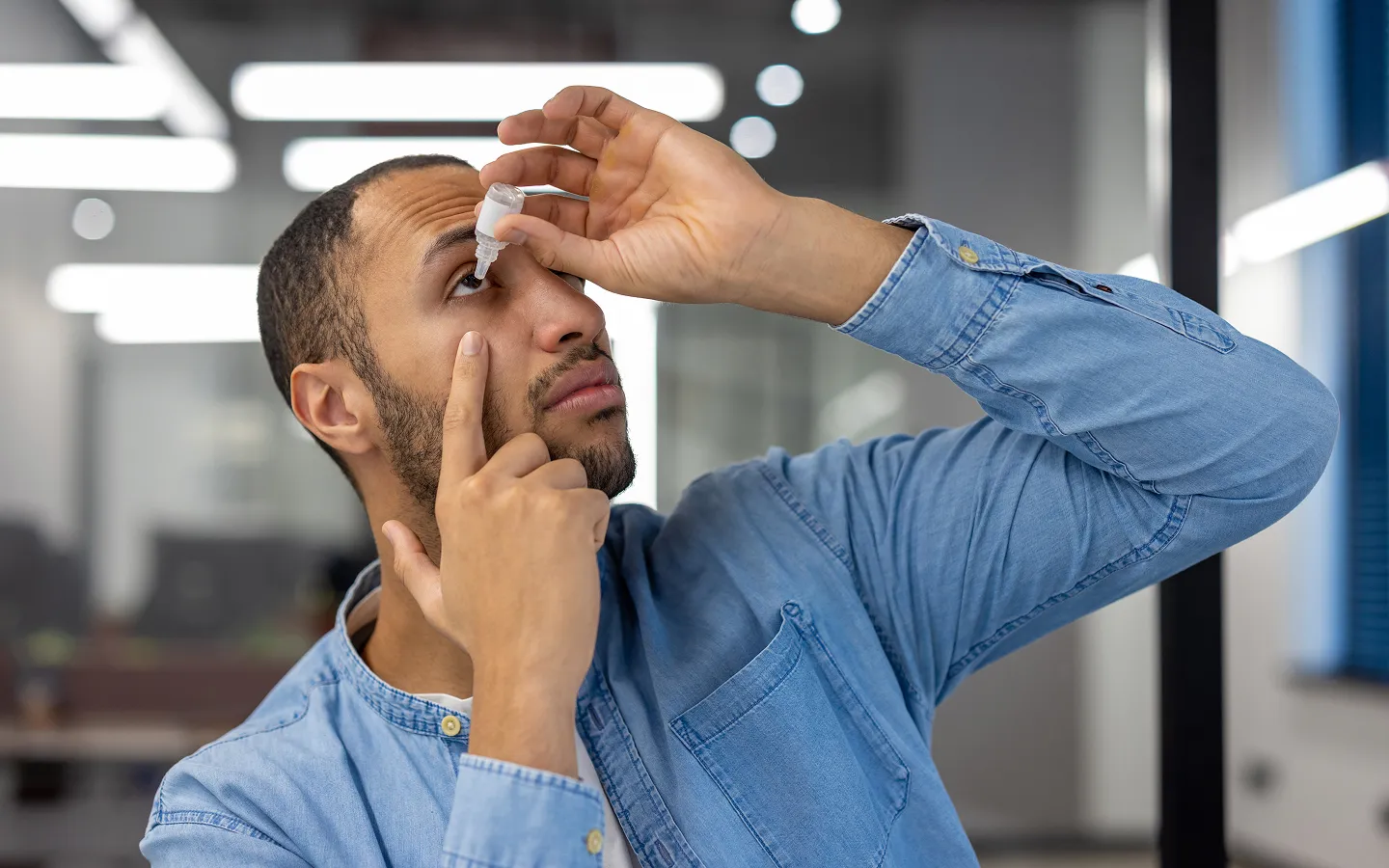Man applying lubricating eye drops for dry eye syndrome treatment and relief